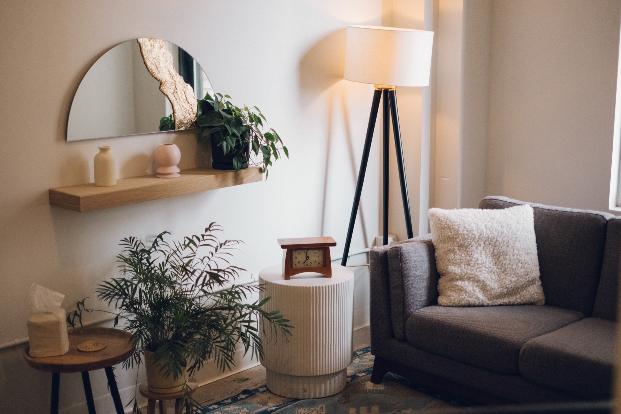 A sofa, lamp, plants, and side table in a warmly lit therapy office.